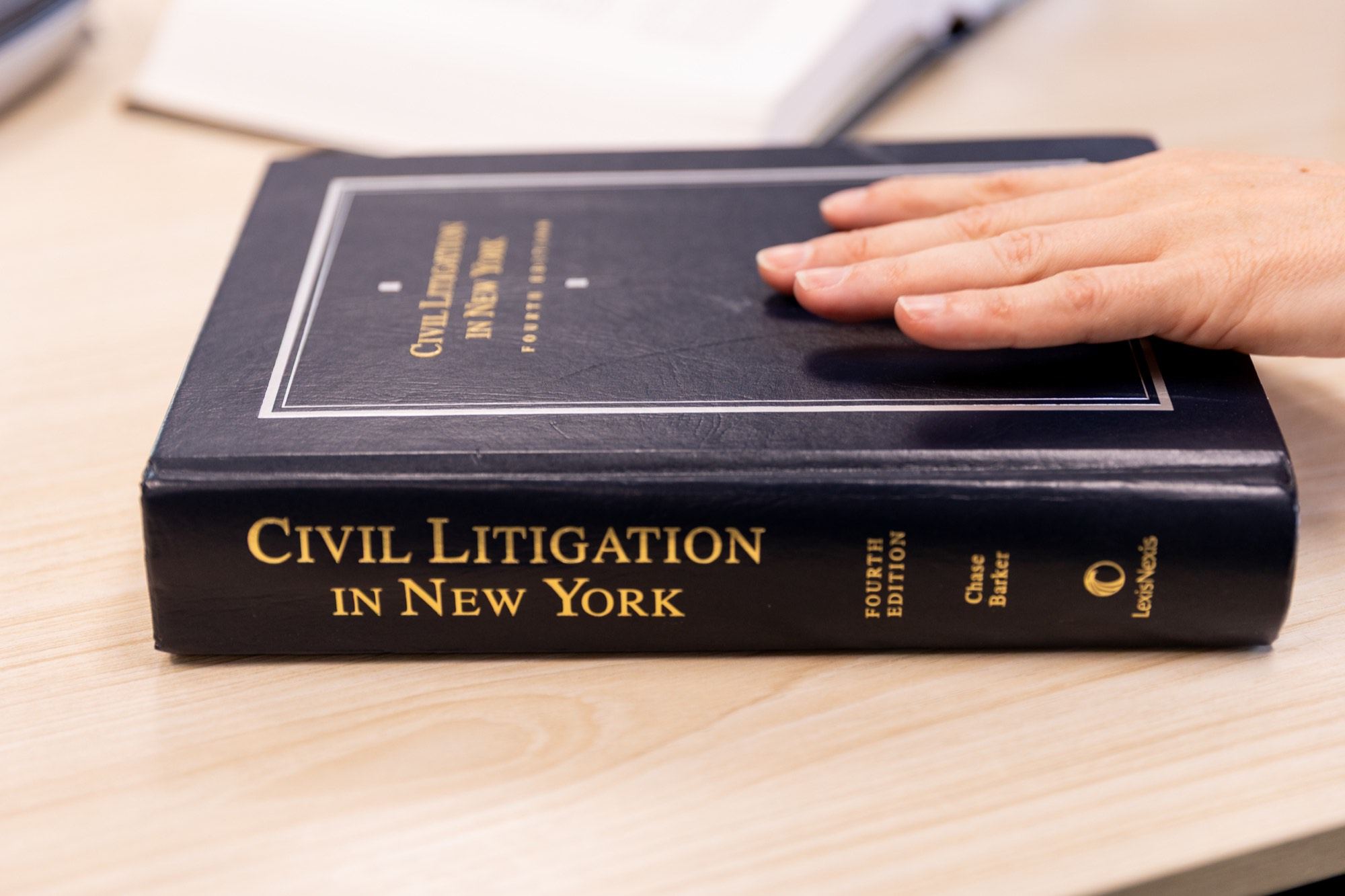 A hand resting on a bound copy of Civil Litigation in New York
