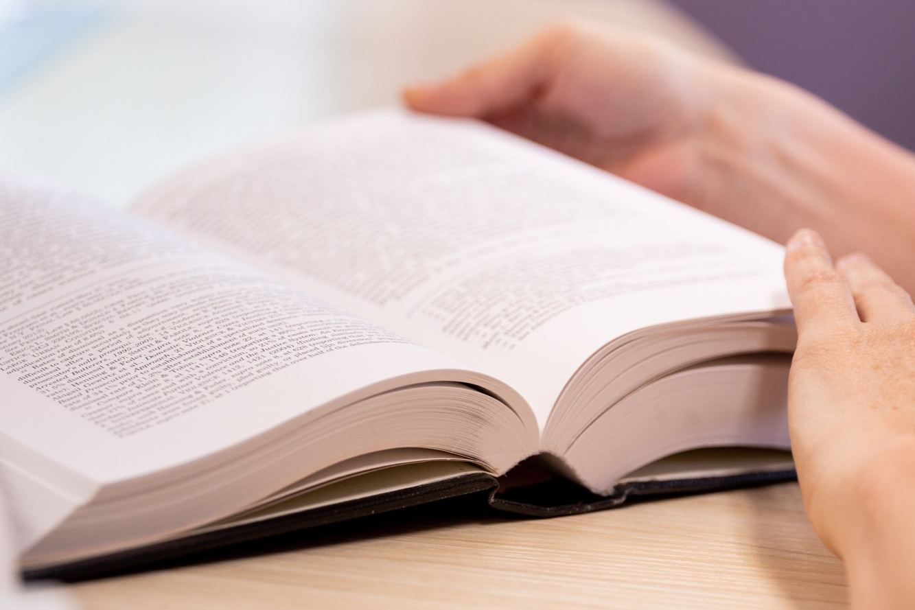 Hands holding open a legal volume on the conference table