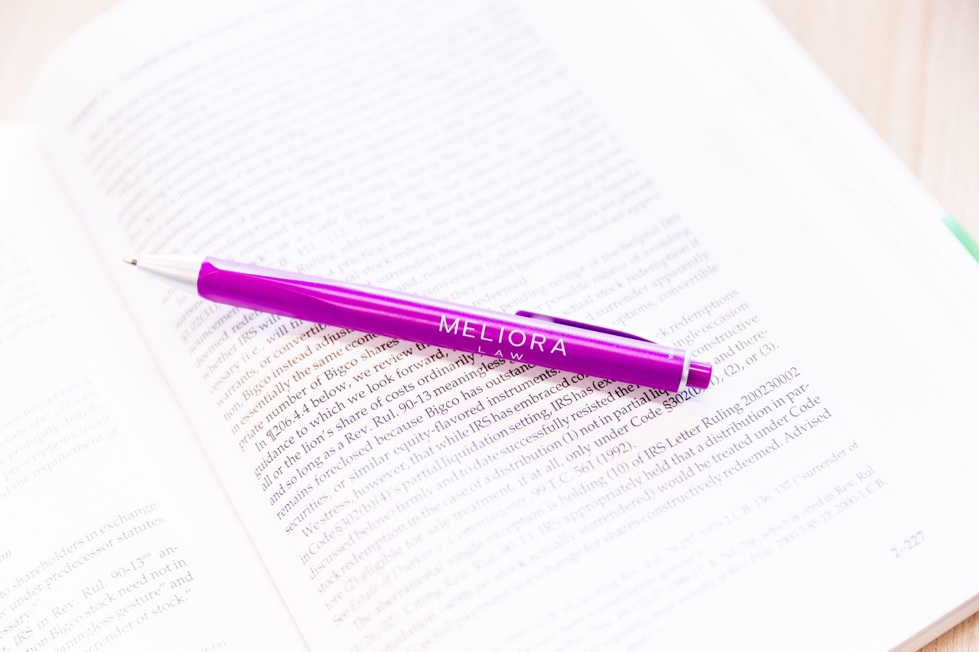 A Meliora-branded pen resting on an open law book